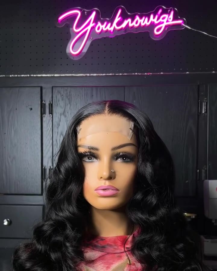 A Youknowigs black body wave unit on a mannequin under the pink Youknowigs neon sign