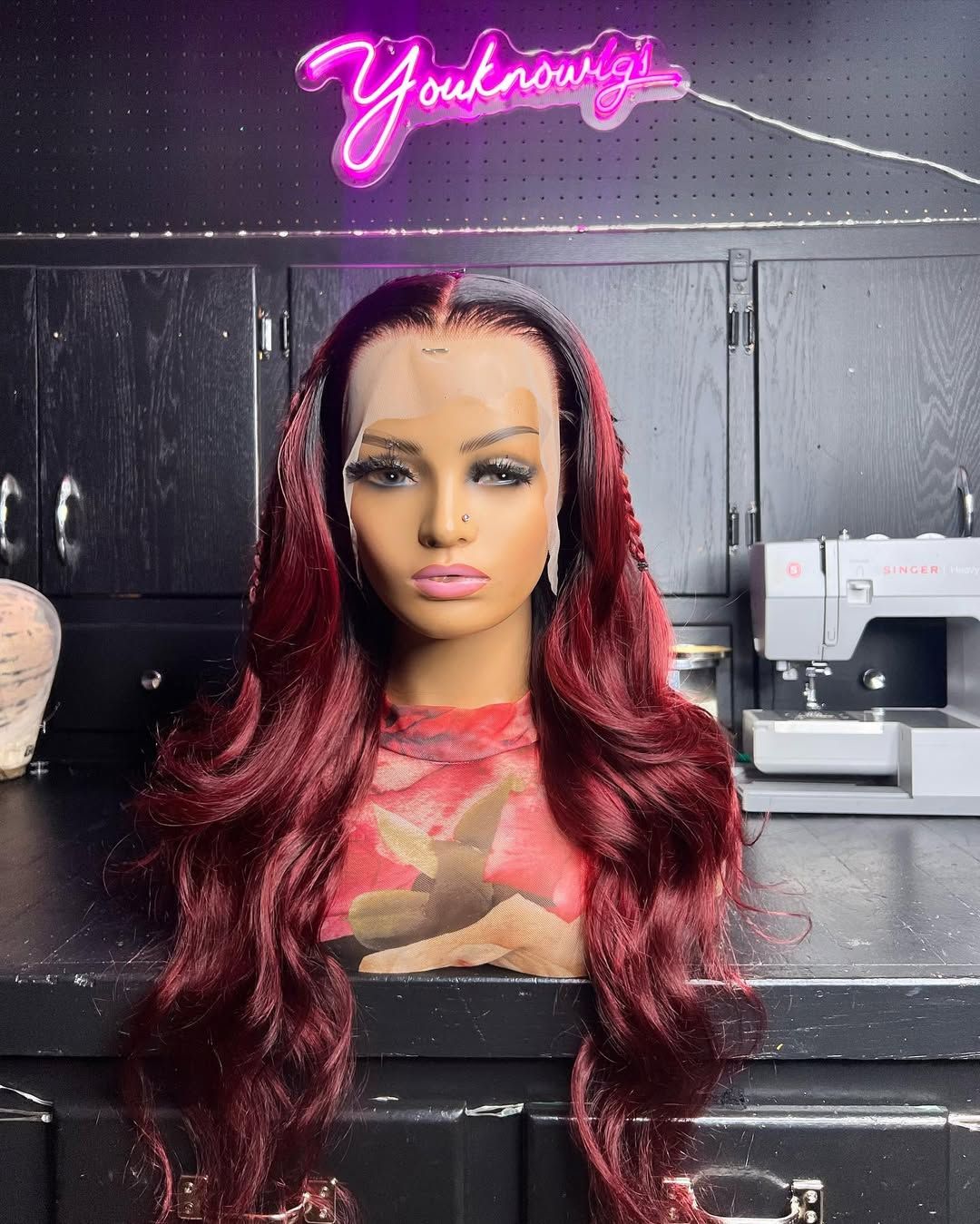 Burgundy ombré deep wave wig on a mannequin under the Youknowigs neon sign